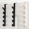 A set of black over-the-door hooks for hanging bags, hats, and scarves on a white door.
