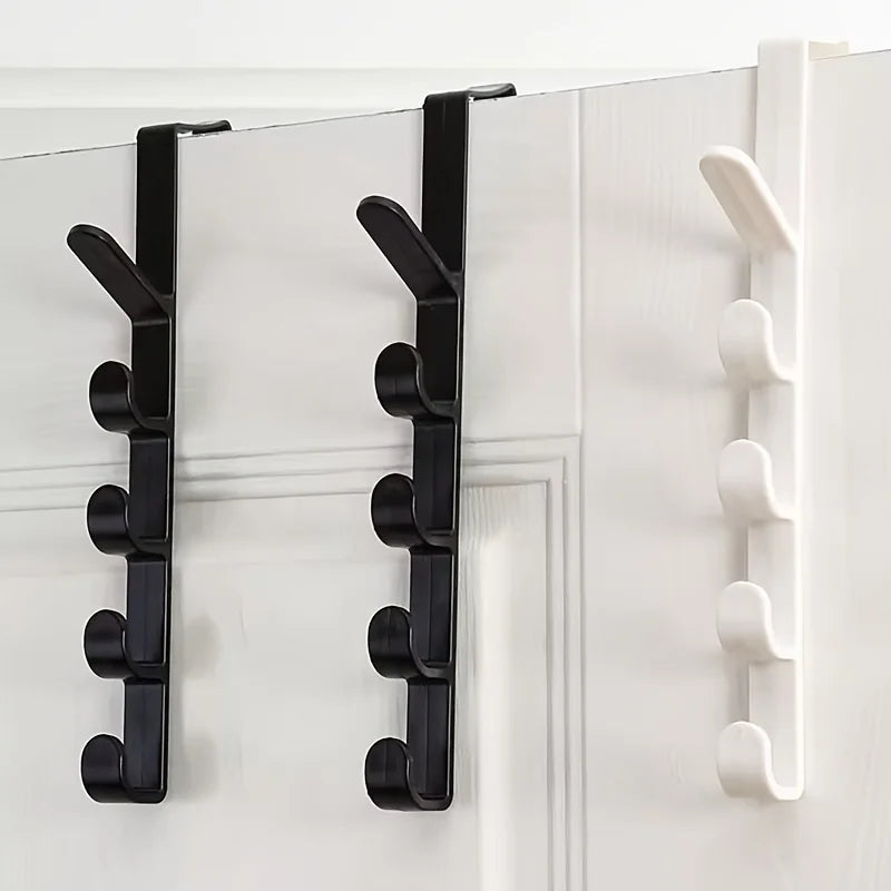 A set of black over-the-door hooks for hanging bags, hats, and scarves on a white door.