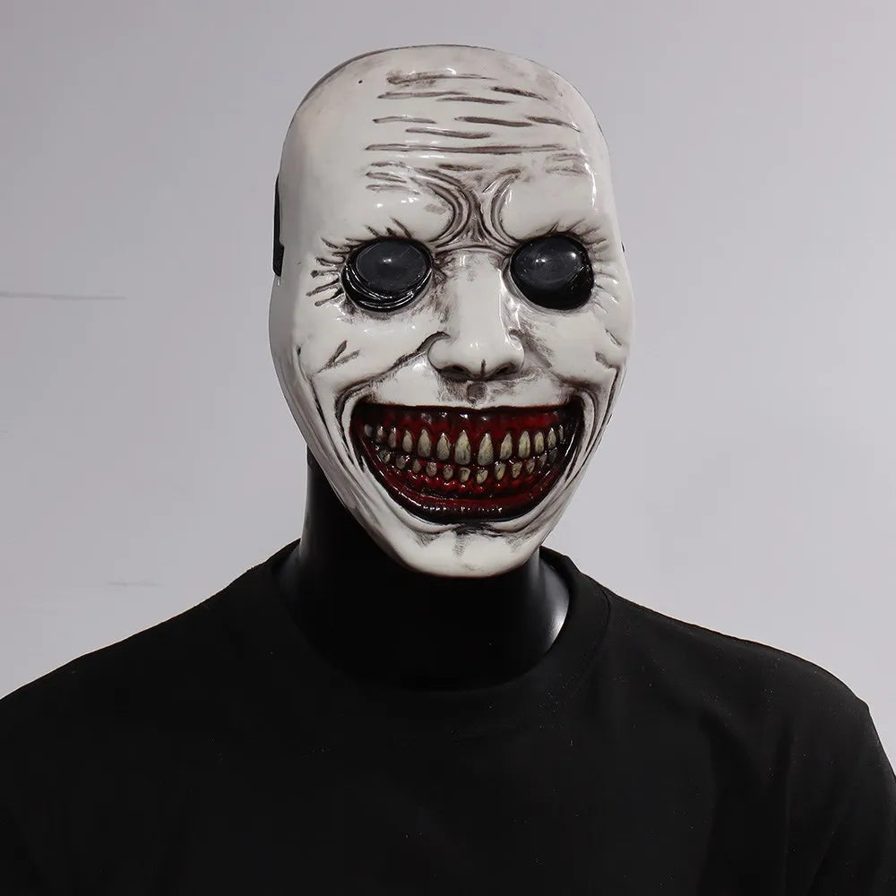 A white demon mask with sunken eyes and a wide, bloody grin displayed on a black mannequin.