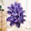 A vibrant purple artificial palm tree with silk leaves displayed in a white vase next to wooden drawers.