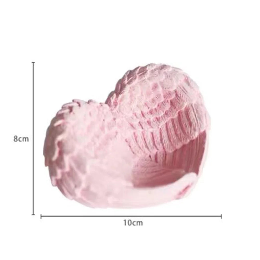 Pink resin sculpture shaped like a heart with textured wings for desk and shelf decor