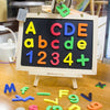 A wooden board displaying magnetic letters and numbers like A, B, C, D, E, 1, 2, 3, 4, and a plus sign.