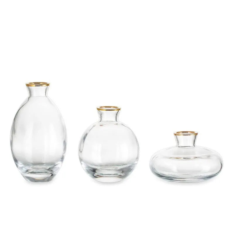A set of three minimalist clear glass bud vases, varying in size and shape.