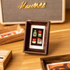 A wooden photo frame displaying three small, colorful cards or polaroids.