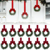 A set of ten artificial Christmas wreaths with red berries and velvet bows hanging on white doors.