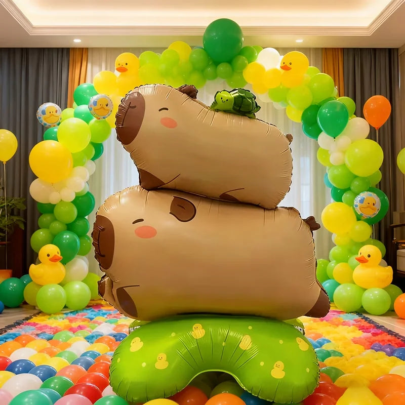 Two standing foil balloons shaped like capybaras and a turtle in various shades of green and yellow for party decor