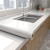 A modern kitchen sink and faucet installed in a white countertop, featuring a marble self-adhesive wallpaper roll.