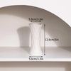 A white ceramic bud vase with a tapered shape is displayed on a shelf.