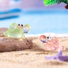 A luminous green resin mini crab decor set rests on light sand next to a pink resin mini crab.