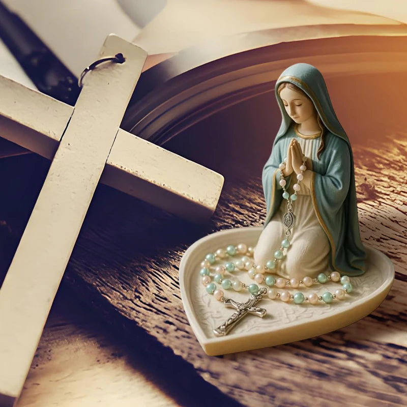 A statue of the Virgin Mary with a rosary holder and Jesus heart on a light-colored tray.