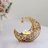 A golden crescent moon candle holder with a star detail sits on a white surface.
