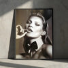 A black and white portrait of Kate Moss with her hair pulled back and a bow tie visible on her collar.