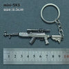 A silver alloy gun model miniature keychain with a realistic finish, shown next to a ruler.
