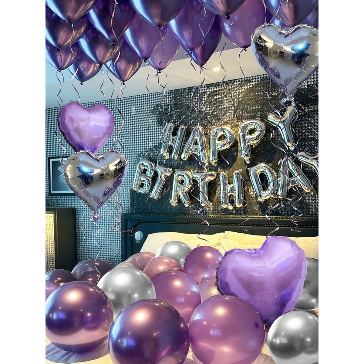 A display of purple and silver heart-shaped balloons and streamers celebrating a birthday.