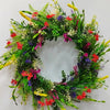 A wreath of artificial wildflowers featuring red, purple, yellow, and white flowers and green foliage for spring and summer d