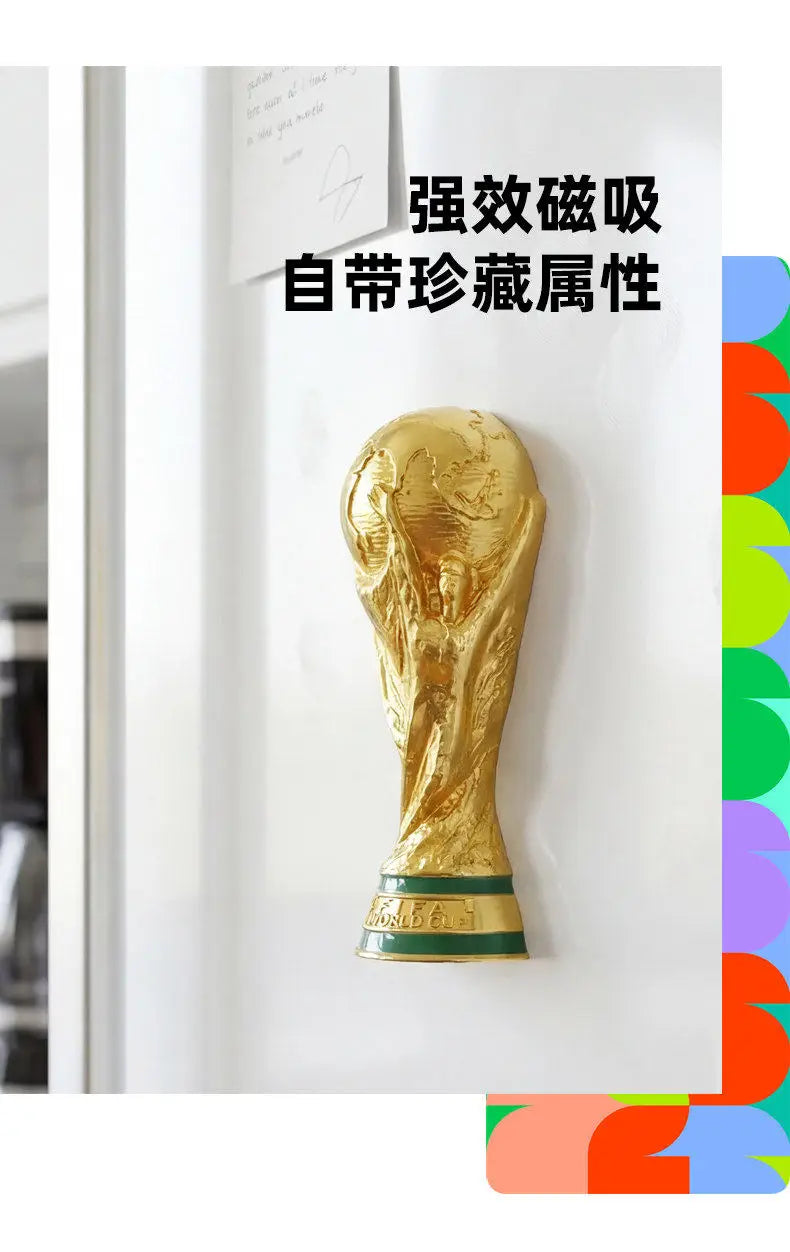 A gold-colored FIFA World Cup trophy fridge magnet displayed on a white surface.