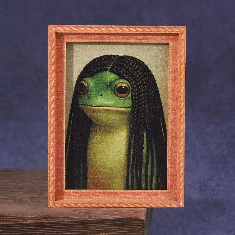 A framed photograph of a green frog with long black hair inside an orange wooden frame.
