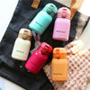 A collection of five pink and light green vacuum insulated coffee mugs arranged on a dark fabric.