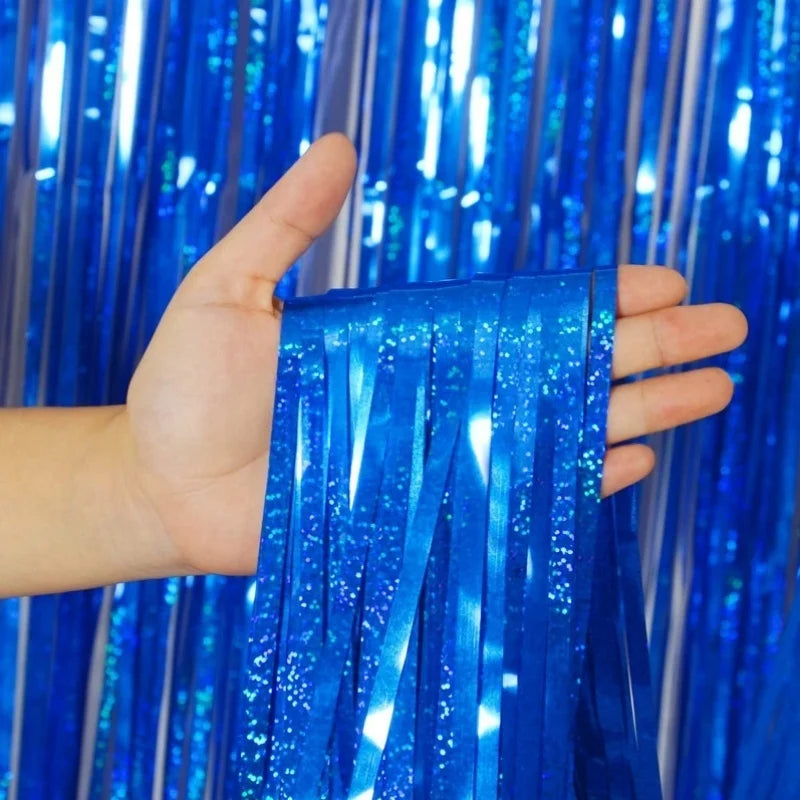 A hand holds a shimmering blue metallic foil tinsel fringe backdrop set.