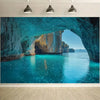 A vibrant turquoise sea cave entrance with sunlight illuminating the clear blue water and surrounding rock formations.