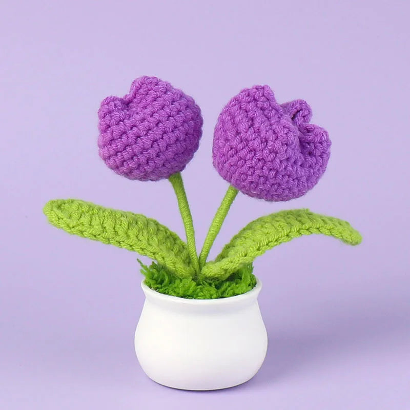 Hand woven crochet purple flowers in a white pot with green leaves