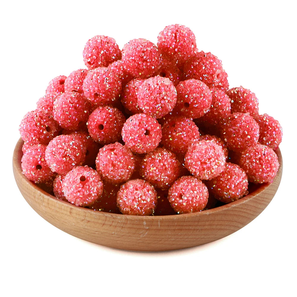 A pile of bright pink textured resin beads for jewelry making in a wooden bowl.
