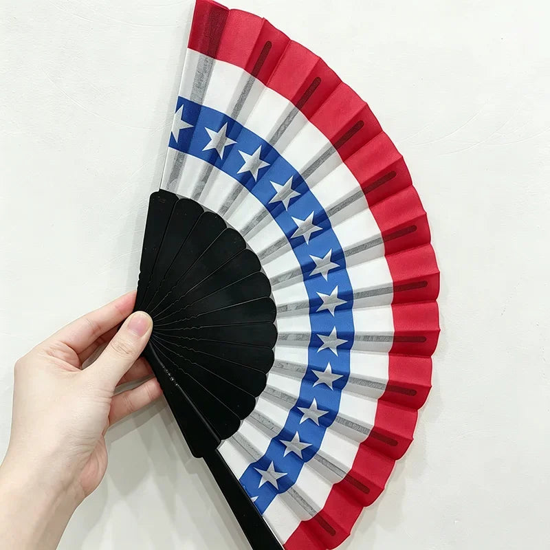 A handheld folding fan featuring a design inspired by the American flag with red, white, and blue stripes and stars.