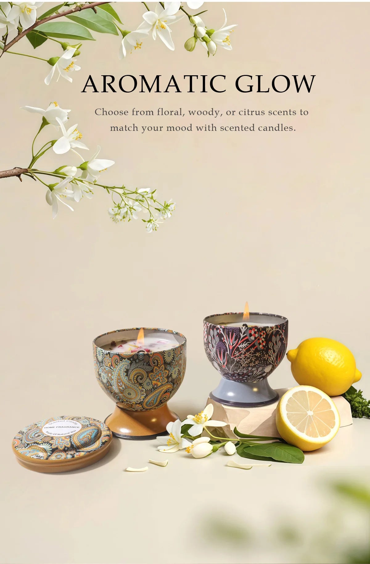 A set of scented candles and a lemon, displayed with white flowers and greenery.