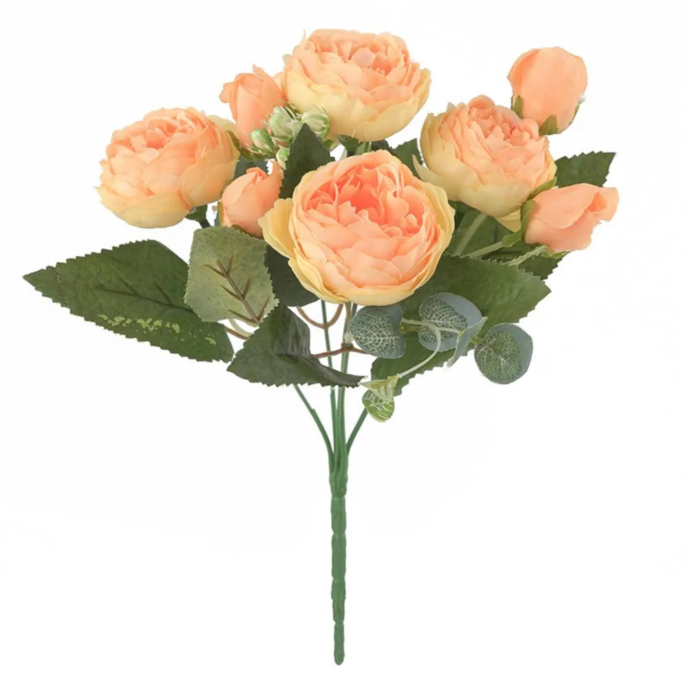 Ein Strauß künstlicher Seidenrosen und Pfingstrosen in Pfirsich- und Cremetönen mit grünen Blättern.