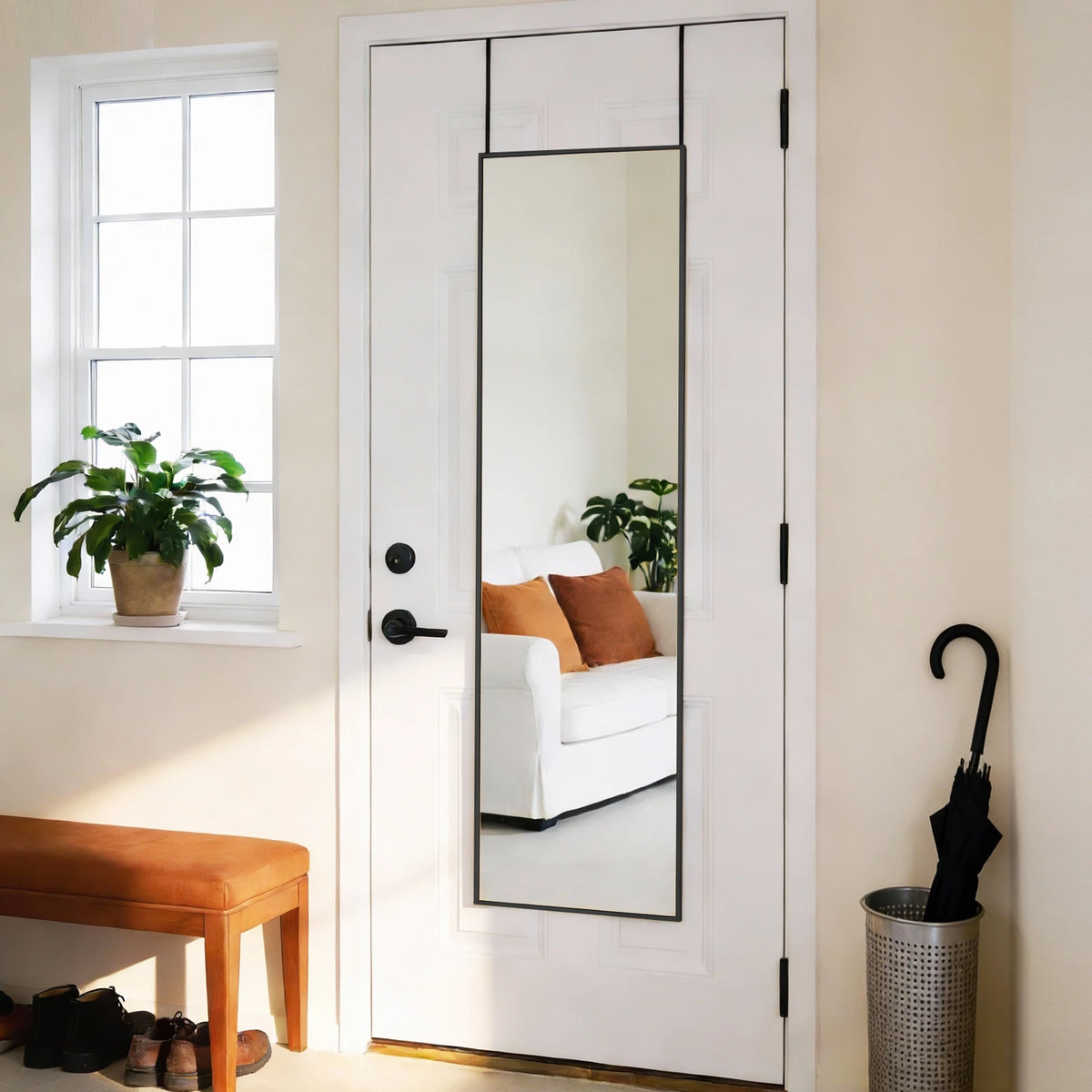 A full-length rectangular mirror with a slim aluminum frame is installed in a white door, reflecting the room.