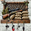 A vintage wooden key hook set featuring a rifle, pine branches, and various keys displayed on a rustic wooden plank.