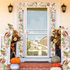 An artificial maple leaf garland frames a white door with glass panels and decorative lanterns.
