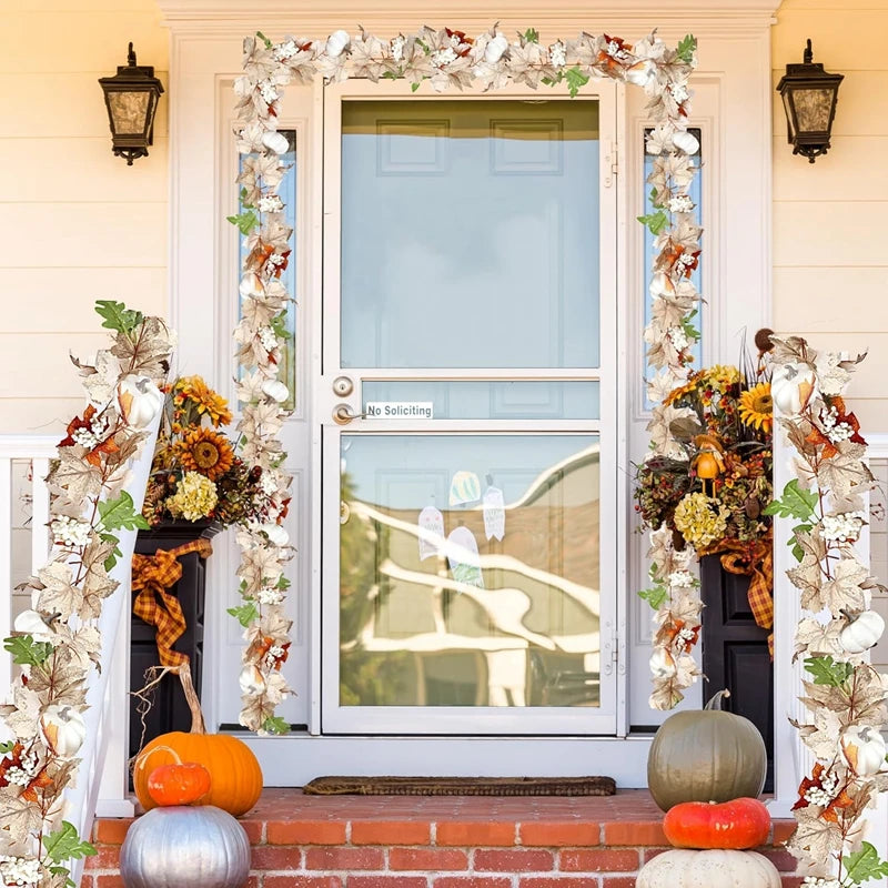 An artificial maple leaf garland frames a white door with glass panels and decorative lanterns.