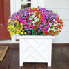 A vibrant bouquet of mixed artificial flowers in purple, pink, white, and orange on a white wooden planter.