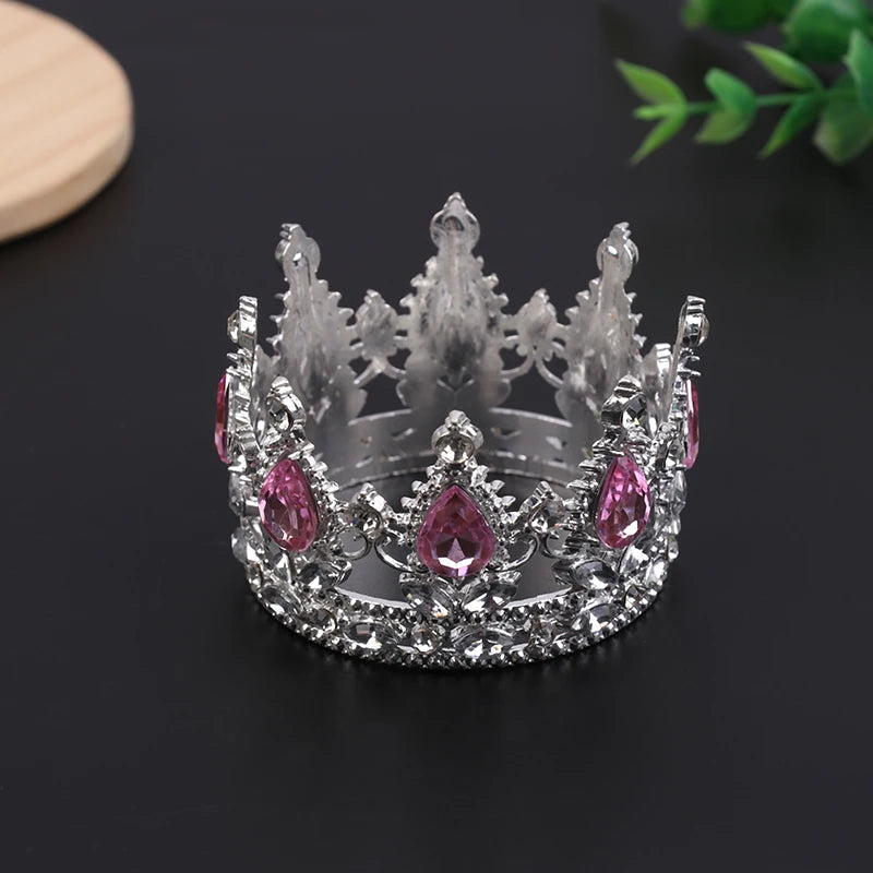A silver tiara crown accessory set featuring pink gemstones and diamonds, displayed on a dark surface.