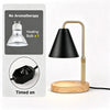 A black adjustable flameless candle warmer lamp with a brass finish and wooden base, shown next to its heating bulb.