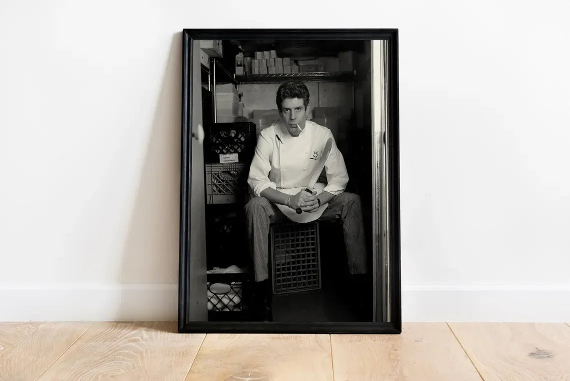 Black and white photograph of a man sitting in a dark setting, framed as wall art.