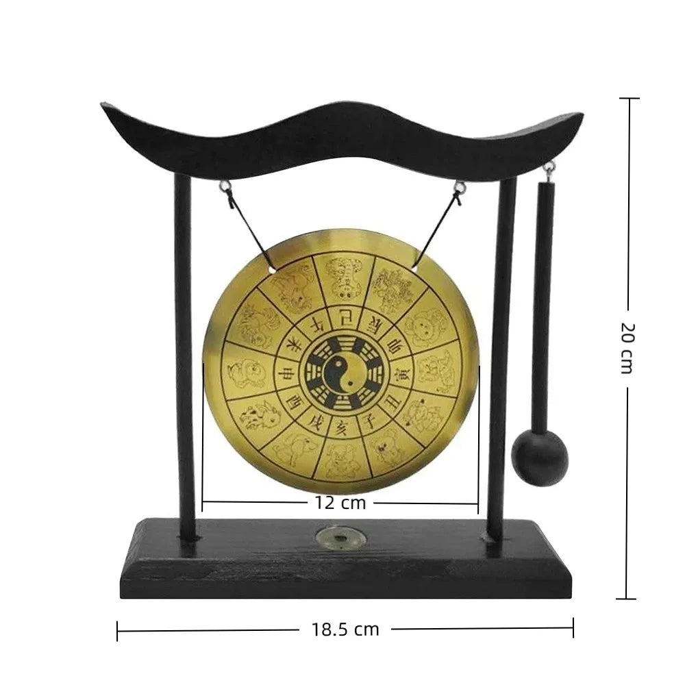 A black desktop zen gong hanging from a curved wooden frame with a brass circular gong.