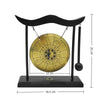 A black desktop zen gong hanging from a curved wooden frame with a brass circular gong.