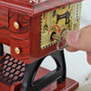 A close-up of a vintage sewing machine music box with a wooden crank and decorative paper inside.