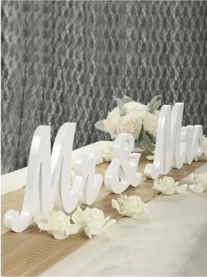 White wooden MR & MRS decorative letters for weddings and home displayed on a table with white flowers.