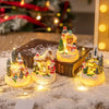 A set of glowing Christmas gingerbread house resin ornaments displayed on a snowy surface.
