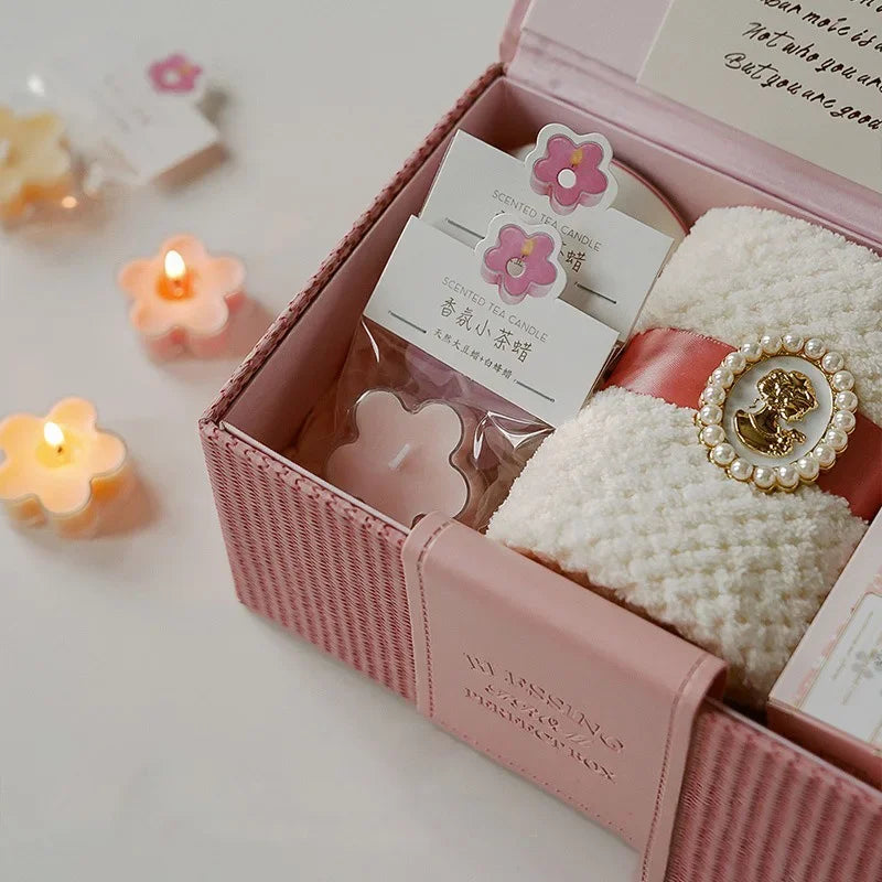 A pink box containing a handmade soy wax flower tea light candle with aromatherapy scent and a decorative gold-rimmed jar.