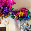 Un amas de ballons en papier d'or et violet suspendus au plafond.