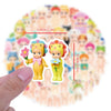 A hand holds a set of cute character decals stickers with measurements marked on the background.