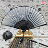 An elegant vintage Chinese folding hand fan with grey and white floral patterns displayed on a wooden stand.