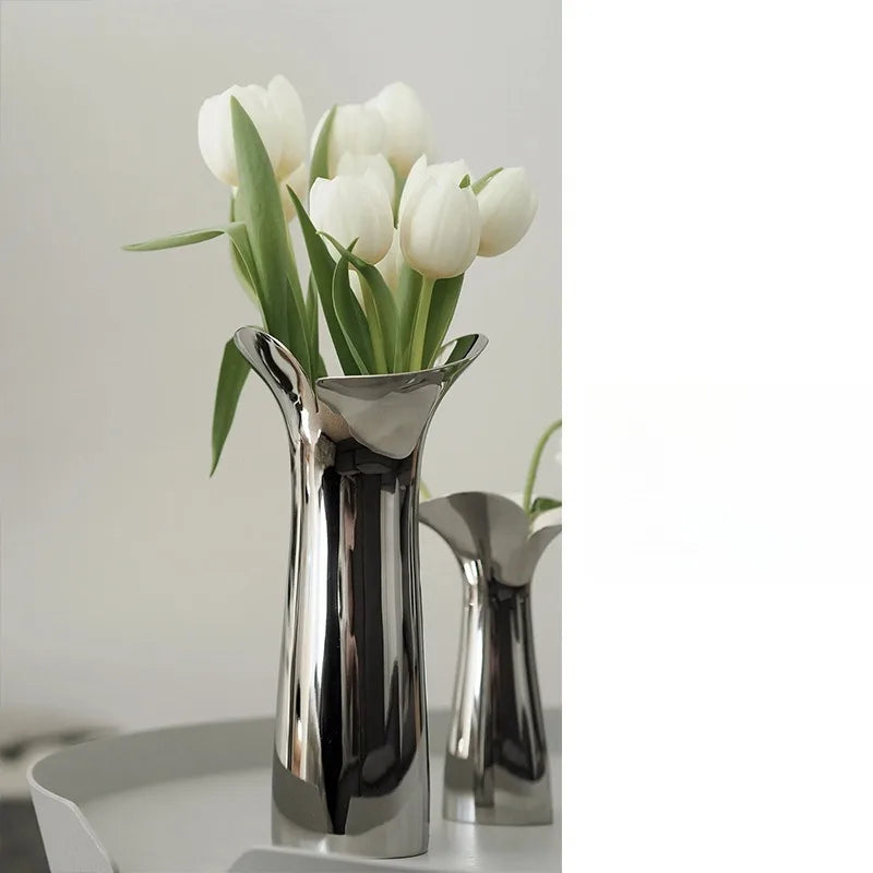 A silver-plated ceramic vase with a Nordic floral design holds white tulips.