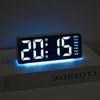 Reloj de alarma LED digital mostrando 20:15 en una superficie blanca con retroiluminación azul.