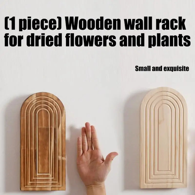 A wooden wall rack for dried flowers and plants with an arched design mounted on a white wall.