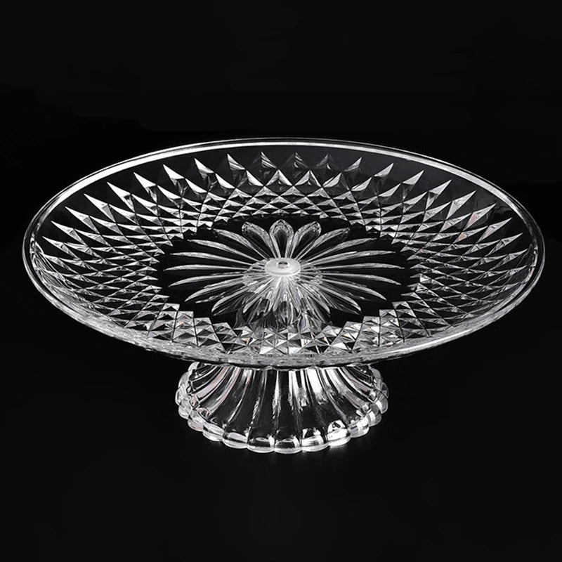 Clear acrylic serving plate with a decorative, sunburst pattern on a pedestal base.